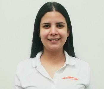 Female employee with black hair smiling in front of a white background